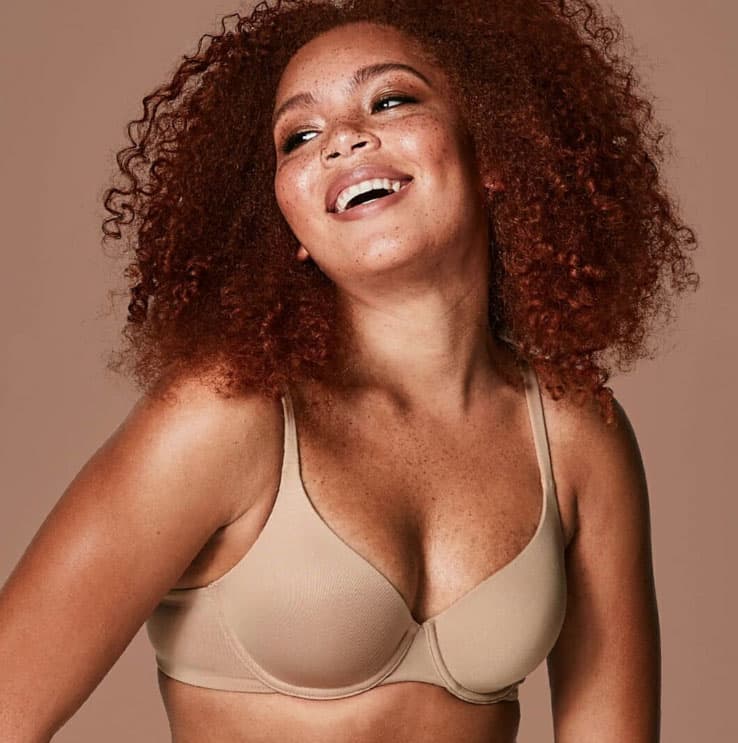 A black woman smiling as she models underwear.